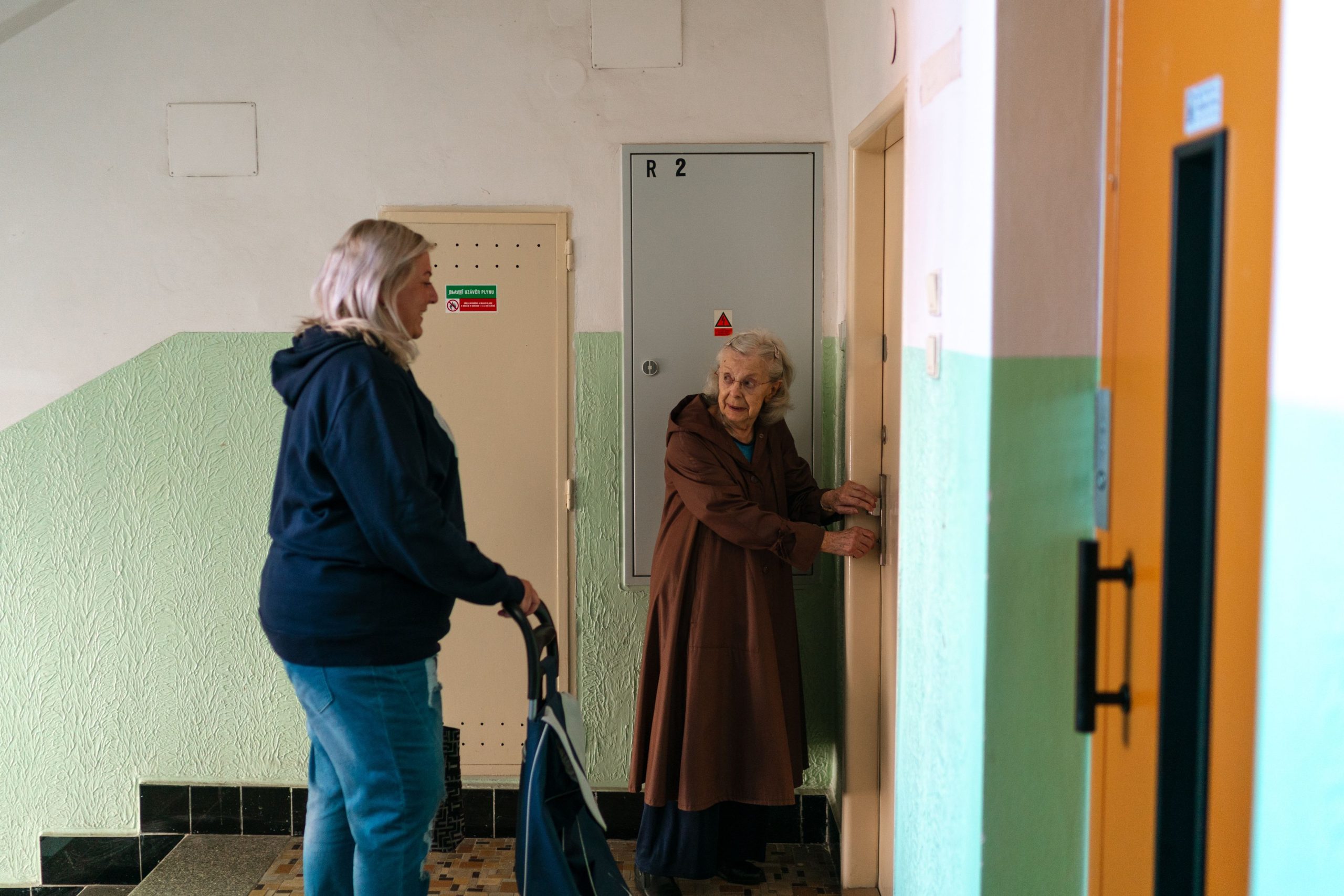 Pflegerin begleitet eine Seniorin mit Rollator an der Wohnungstür